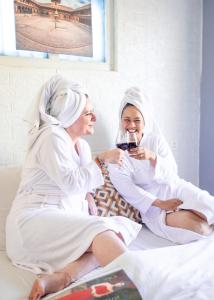 two women sitting on a bed drinking wine at Nyadha House Bed & Breakfast in Pātan
