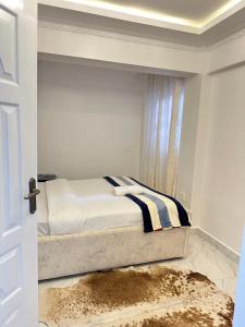 a white bedroom with a bed with a window at Regency Stays III in Eldoret
