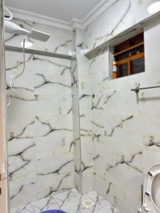 uma casa de banho com paredes em mármore branco e um chuveiro em Regency Stays III em Eldoret