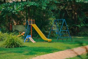 un parque infantil con un tobogán en un patio en Carina Beach Resort - 10mins walk to Benaulim Beach, en Benaulim