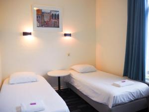 a room with two beds and a table and a window at Euphemia Budget Old City Canal Zone in Amsterdam
