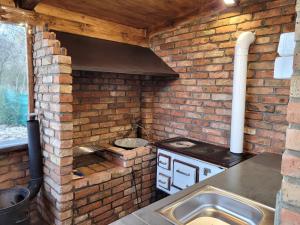 a brick kitchen with a stove and a sink at Végvári Vendégház in Magyarbóly