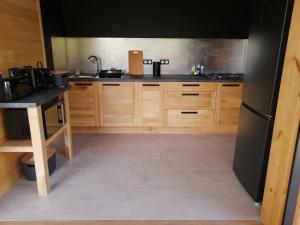 uma cozinha com armários de madeira e um frigorífico preto em NIAOULI LODGE em Bourail