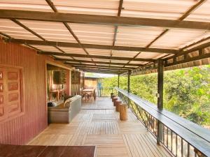 eine überdachte Terrasse mit einem Sofa und Stühlen auf einem Haus in der Unterkunft Backpacker Hostel and Jungle Trekking in Banlung