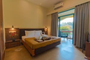 ein Hotelzimmer mit einem Bett und einem Balkon in der Unterkunft Carina Beach Resort - 10mins walk to Benaulim Beach in Benaulim