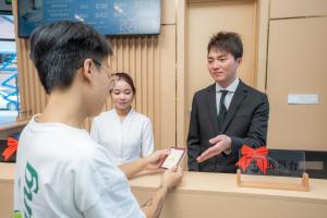 a man and a woman standing behind a counter with a person holding a phone at ARK HOTEL in Phnom Penh