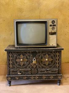 une vieille télévision assise au-dessus d'une commode dans l'établissement بيت النحوي التراثي _ Bait Al Nahwai, à Al Hamra