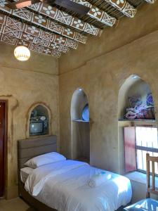 a bedroom with a bed in a room with arched windows at بيت النحوي التراثي _ Bait Al Nahwai in Al Ḩamrāʼ