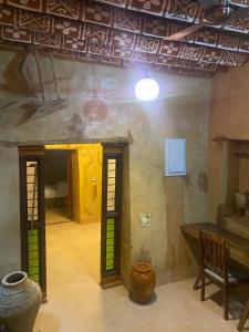Habitación con mesa y jarrones en el suelo en بيت النحوي التراثي _ Bait Al Nahwai, en Al Ḩamrāʼ