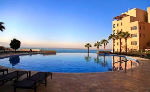 uma grande piscina com palmeiras e um edifício em E25 Samarah Resort Apartments em Sowayma