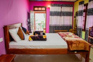 Schlafzimmer mit einem Bett mit rosa Wänden in der Unterkunft Nine Arch Homestay in Ella