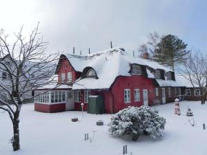 a red barn with snow on top of it at Hüs Sanskiin Ferienwohnung *Aawerkant* in Süddorf +54 photos