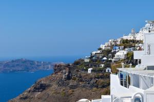 vistas a una colina con edificios blancos y al océano en Aeolos Art & Eco Suites Adults Only, en Imerovigli