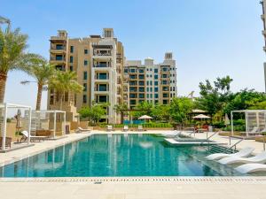a swimming pool with palm trees and buildings at FAM Living - Rahaal 1BR Bliss in Madinat Jumeirah Living in Dubai