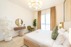 FAM Living - Serene 1BR Haven in Madinat Jumeirah Living في دبي: غرفة نوم بيضاء مع سرير كبير ومرآة