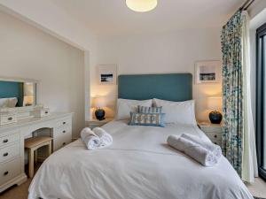 um quarto com uma grande cama branca com toalhas em 2 Bed in Westward Ho 91748 em Northam