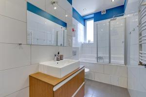 a white bathroom with a sink and a tub at Downtown Apartments City Center Art House - Family Stay in Gdańsk