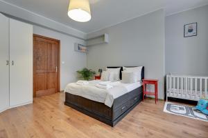a bedroom with a bed and a crib in it at Downtown Apartments City Center Art House - Family Stay in Gdańsk