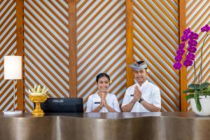 un hombre y una mujer sentados en una mesa con un portátil en The Hava Ubud A Pramana Experience, en Ubud