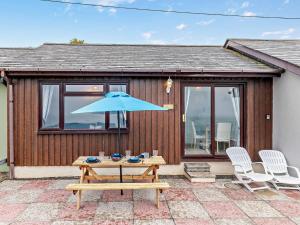 a picnic table with a blue umbrella on a patio at 1 Bed in Plymouth 91835 in Turnchapel