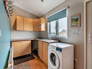 een wasruimte met een wasmachine en een raam bij 3 Bed in Livingston 91829 in Forth