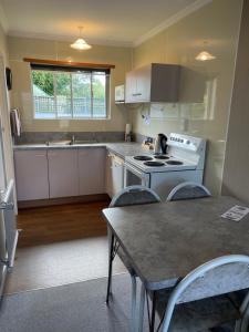 uma cozinha com um fogão e uma mesa com cadeiras em Alexandra Motor Lodge em Alexandra