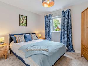 een slaapkamer met een bed met blauwe gordijnen en een raam bij 3 Bed in Gower 91729 