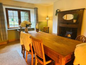 a dining room with a wooden table and a fireplace at Rosemount Cottage TWO - Highland Cottage in Garve