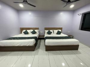 two beds in a room with white walls at Green Valley Family Resort in Amarkantak