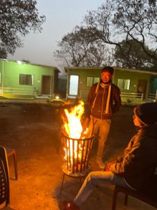 a man is standing next to a fire at Green Valley Family Resort in Amarkantak