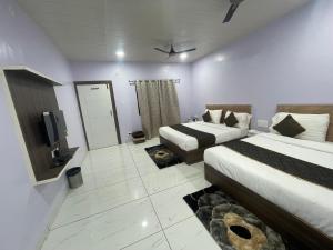 a hotel room with two beds and a tv at Green Valley Family Resort in Amarkantak
