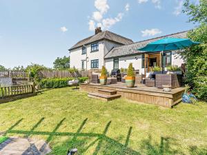 ein Haus mit einem Hinterhof mit einer Terrasse und einem Sonnenschirm in der Unterkunft 2 Bed in St Clears 92026 in St Clears