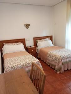 a bedroom with two beds and a wooden table at Hospedaje Magallanes in Santander