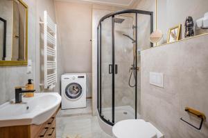 a bathroom with a shower and a sink and a washing machine at Villa Sophia in Biskupiec