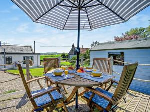 una mesa de madera con una sombrilla en el patio en 2 Bed in Bamburgh 92196, en Belford