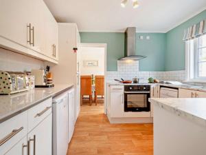 a kitchen with white cabinets and blue walls at 3 Bed in West Lulworth 92106 in West Lulworth