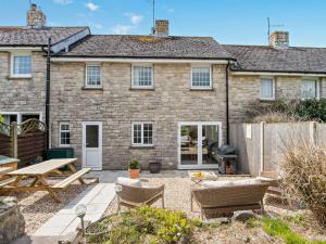 an exterior view of a brick house with a patio at 3 Bed in West Lulworth 92106 in West Lulworth