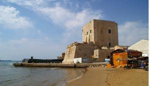 a building on the beach next to the water at Casa Vacanze J&F in Pozzallo