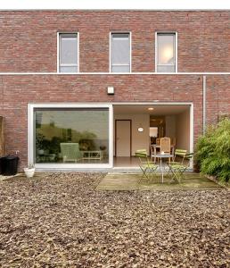 uma casa de tijolos com um pátio com cadeiras e uma mesa em House with private parking & sauna near city centre and transport em Roeselare