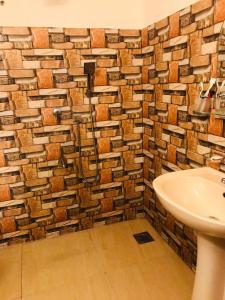 a bathroom with a sink and a brick wall at NEWCINNAMONVILLA in Habaraduwa