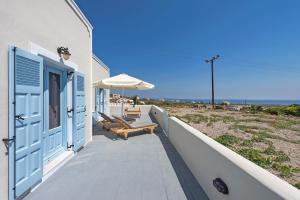 a beach house with blue doors and chairs and an umbrella at Ann-Margo House in Fira