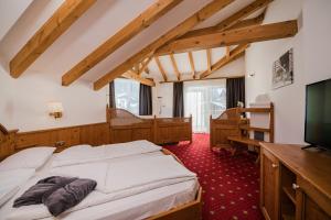 a bedroom with a bed and a flat screen tv at Hotel Laurin in Dobbiaco