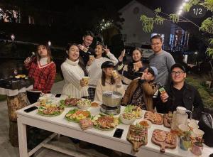 a group of people standing around a table with food at Scent Bungalow Hotel in Da Lat