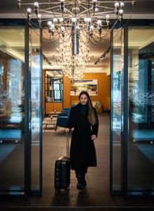 a woman standing in a lobby with a suitcase at HVD Grand Hotel Suhl Business & Leisure in Suhl