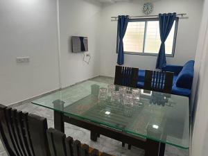 une salle à manger avec une table et des chaises en verre dans l'établissement Soumil 102, à Chinchwad