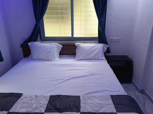 a bed with two pillows in a bedroom with a window at Soumil 102 in Chinchwad