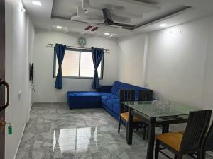 a living room with a blue couch and a table at Soumil 102 in Chinchwad