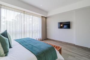 een slaapkamer met een bed en een televisie aan de muur bij Stay Regency Menlyn in Pretoria