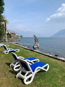 a group of lounge chairs and a bird statue next to the water at Hotel Garni Rivabella au Lac in Brissago