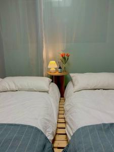 two beds in a room with a table with a lamp at Raon house in Suwon